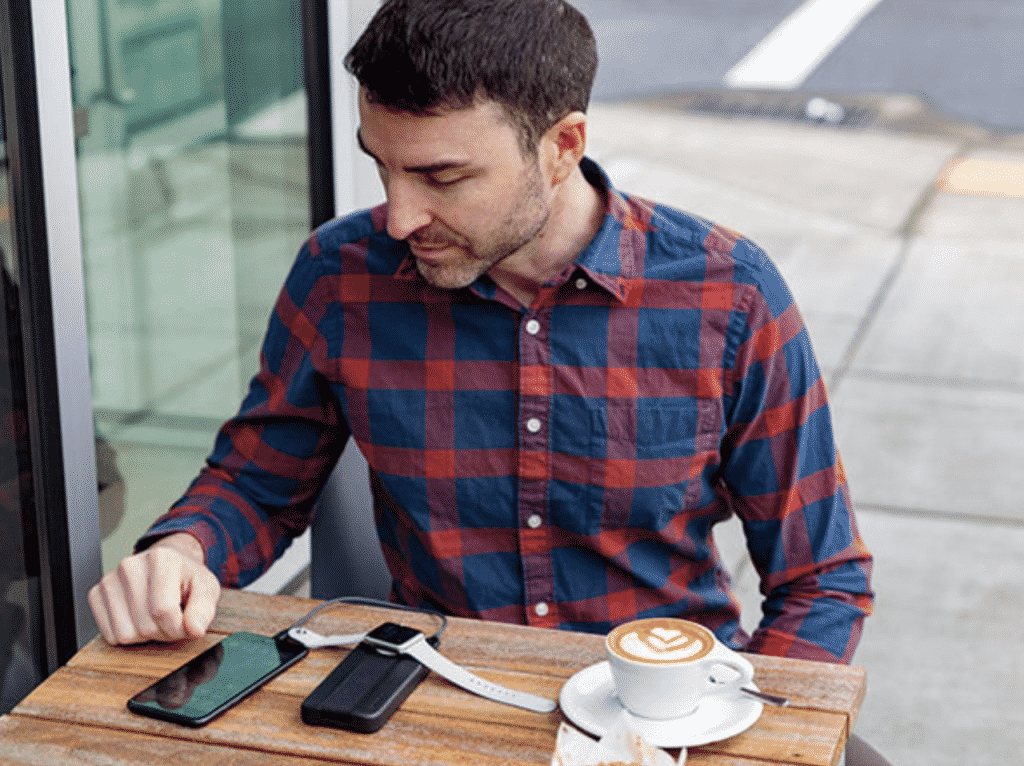 A man with a coffee using the BatteryPro portable charger for iPhone and Apple Watch