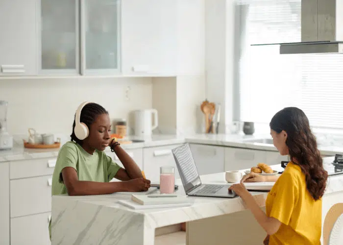 Roommates Studying in Kitchen Using Laptop and Phone